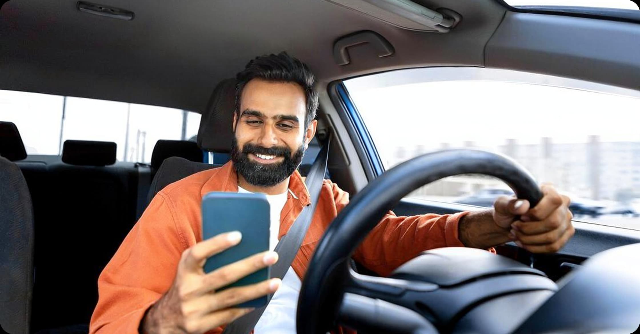 Driver smiling while checking phone inside a car